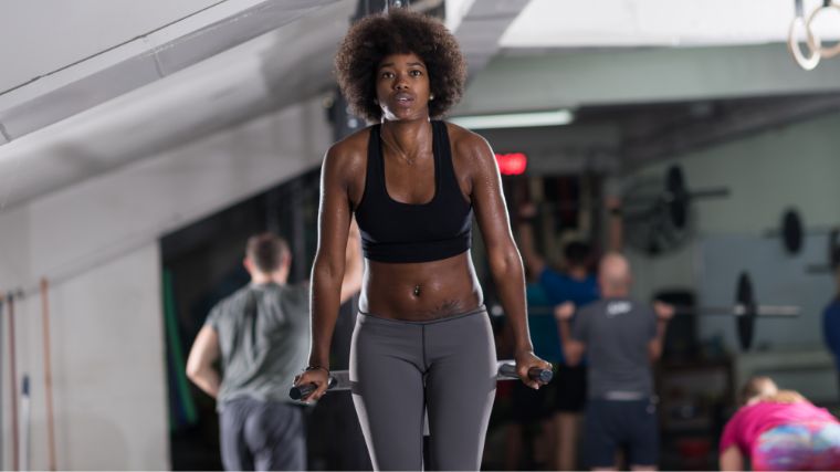 A person in a black sports bra doing dips.