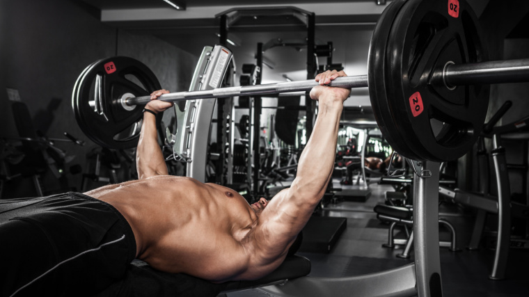 A bodybuilder bench pressing in the gym.