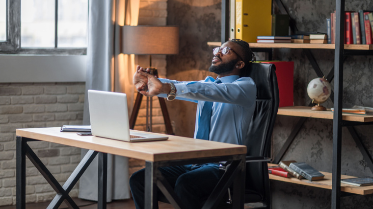 An employee stretching their limbs in their workplace.