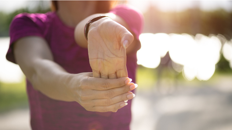 A person doing wrist stretching exercise outdoor.