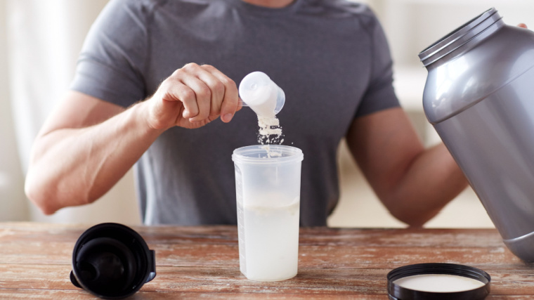 A person pouring some powdered supplements in a container with water.