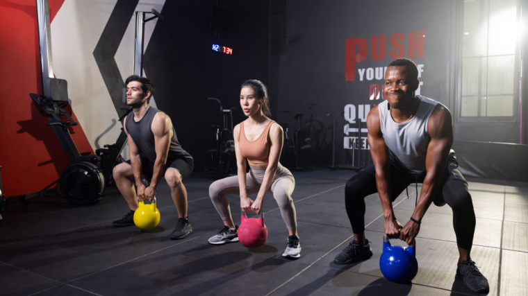 Group of people lifting kettlebell and while doing squat training