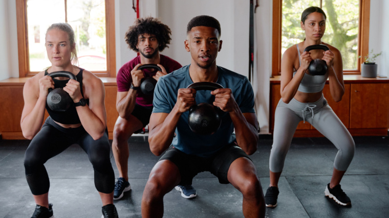 A group of people doing kettlebell squat