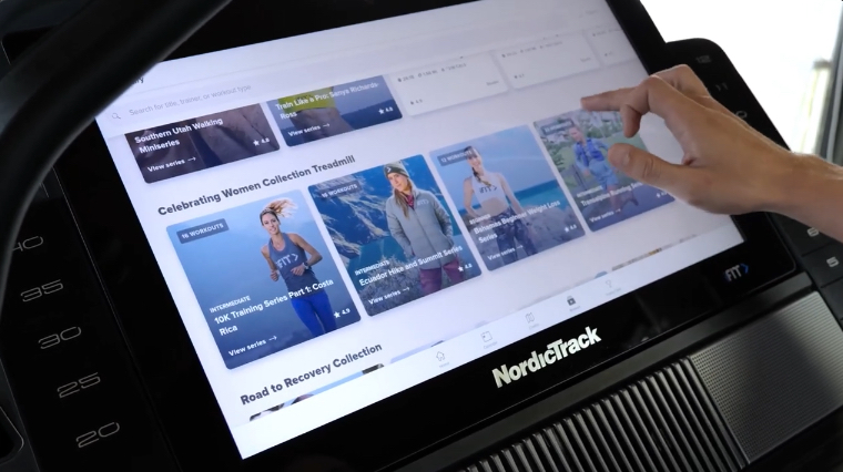 A hand can be seen browsing iFit on the NordicTrack Commercial X22i