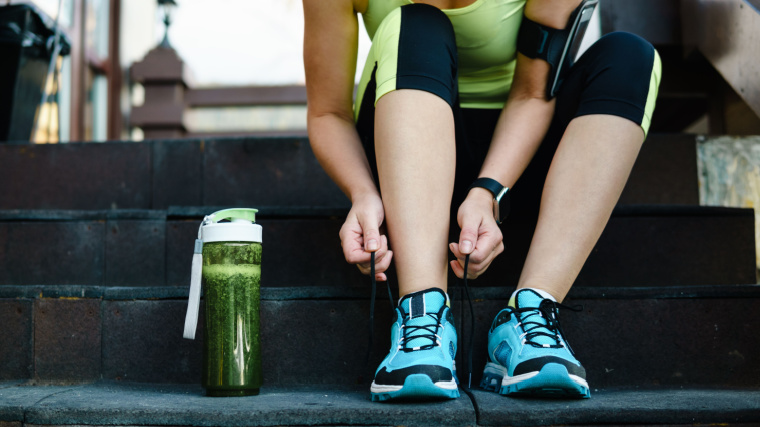 A fit person lacing up shoelace, preparing for an exercise.