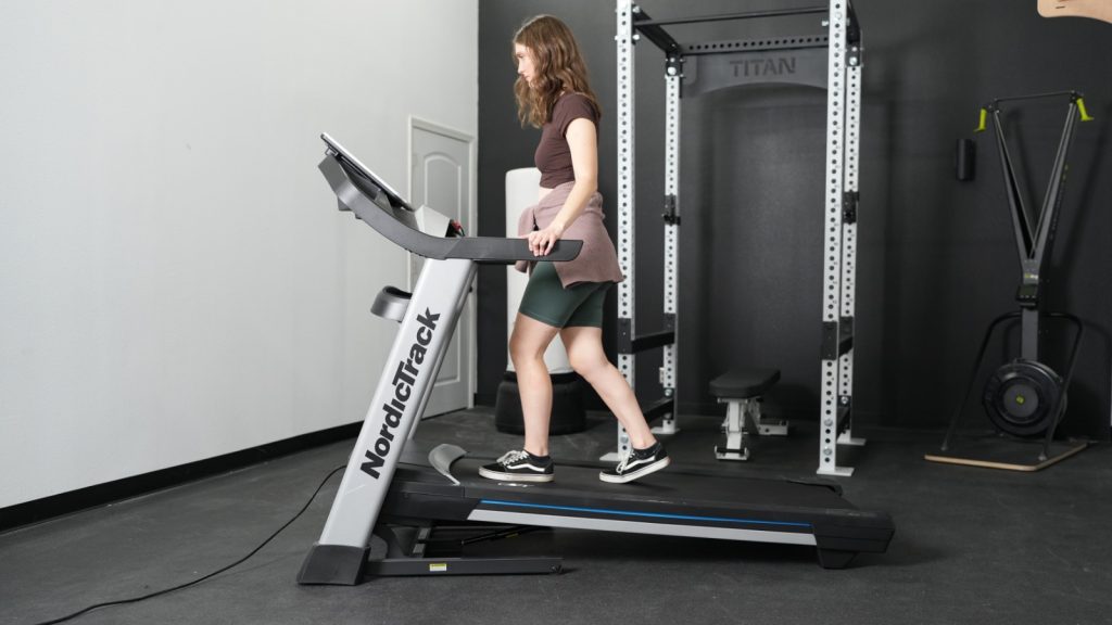 A person is walking on the NordicTrack EXP 7i treadmill using the incline feature
