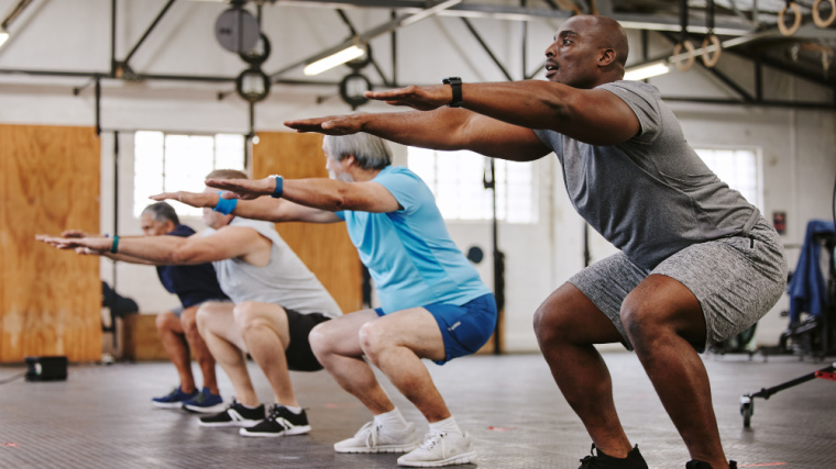 Fit individuals performing squats in the gym.