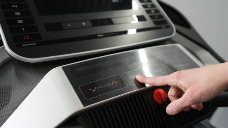 Close up of a hand pushing the start button on the NordicTrack EXP 7i treadmill.