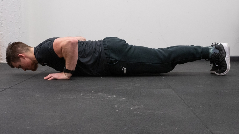A person doing the second push-up position with the body close to the ground.