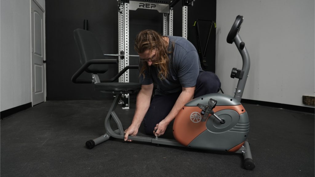 Our tester adjusts the knob on the base of the Marcy Recumbent Bike.